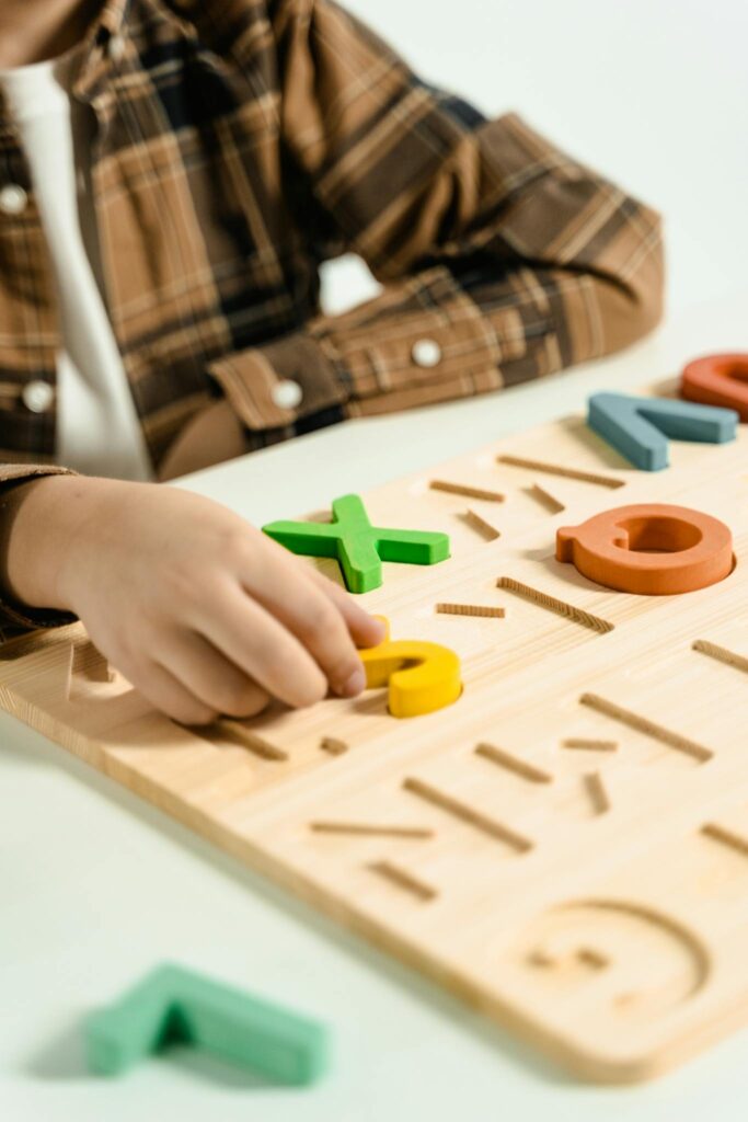 Close-up of a child playing with a colorful alphabet puzzle board.